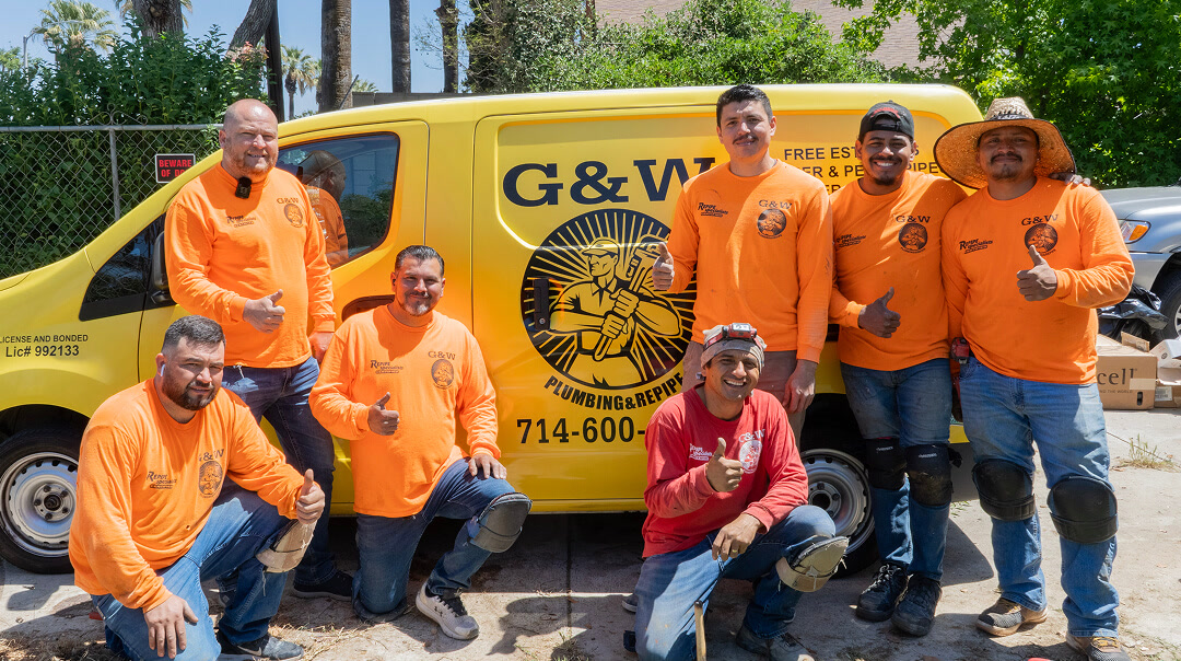 G & W Plumbing team in front of a company service van